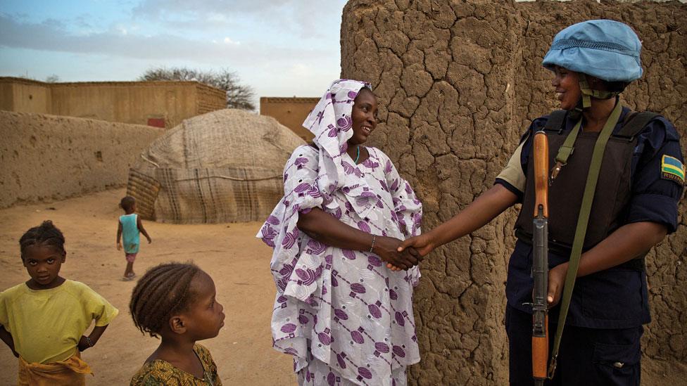 A peacekeeper shaking the hands of a woman in Mali