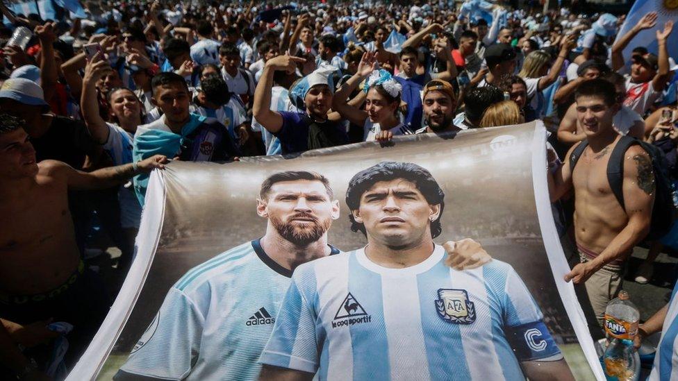 Cefnogwyr Ariannin yn gafael mewn baner o Lionel Messi a Diego Maradona