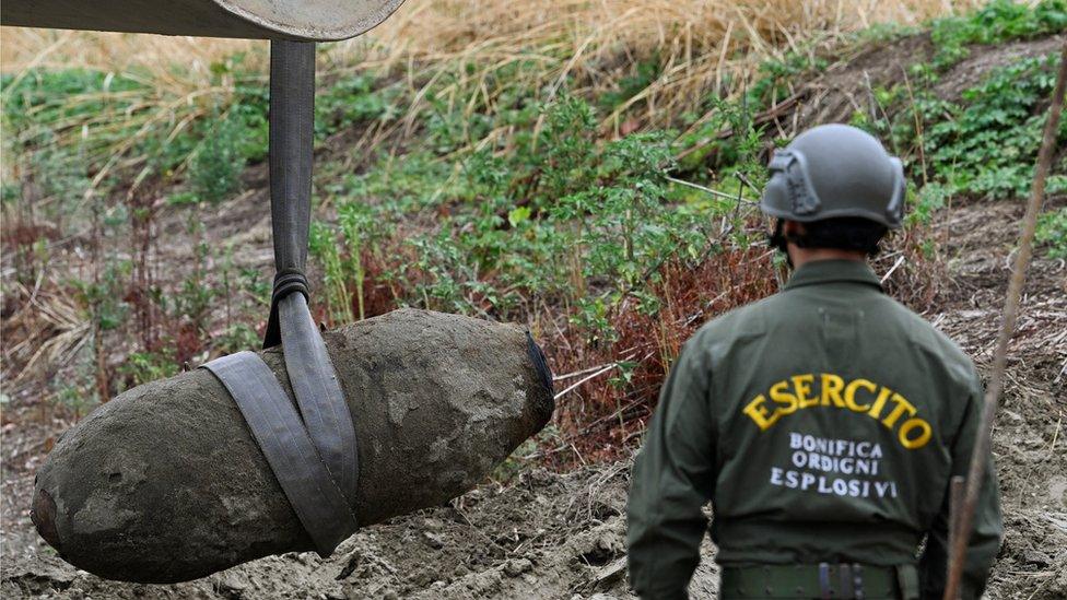 A soldier watches a bomb being removed.