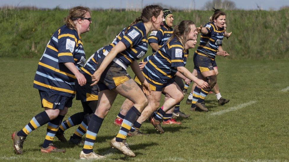 A group of muddy women playing rugby