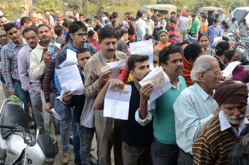 Indian people queue outside a bank as they wait to deposit and exchange 500 and 1000 rupee notes in Amritsar on November 13, 2016.