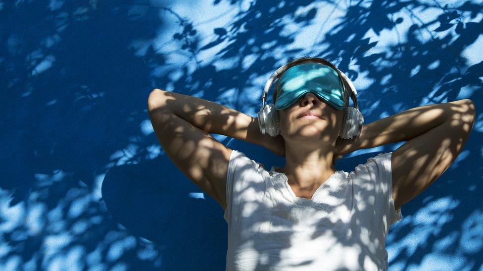 woman in eye shade listening to music