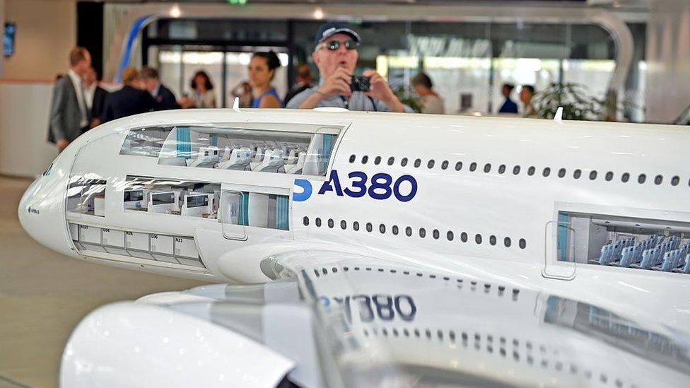 A visitor takes a photo of a model Airbus plane at the company's headquarters outside Toulouse