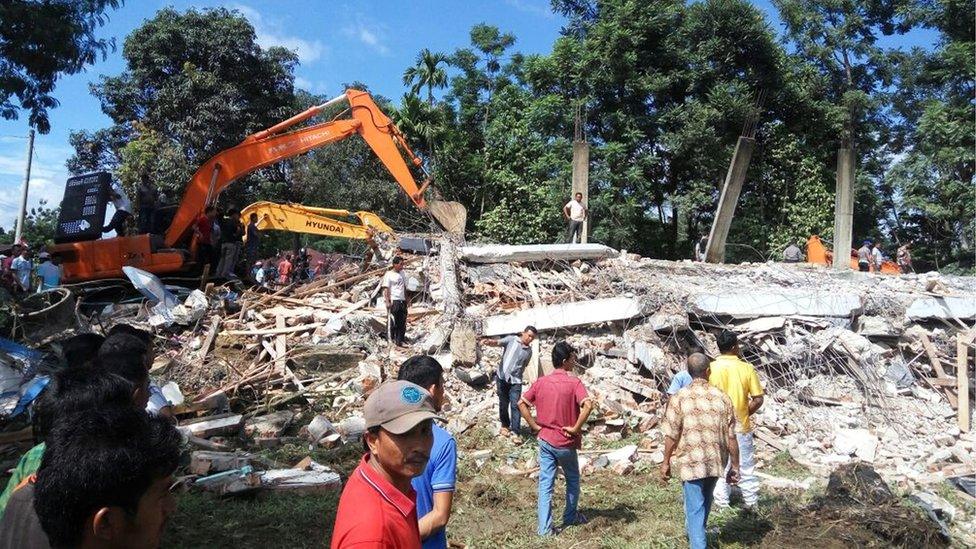 Rescuers use heavy machine to search for survivors under the rubble in Pidie Jaya, Aceh province, Indonesia, 7 December 2016.