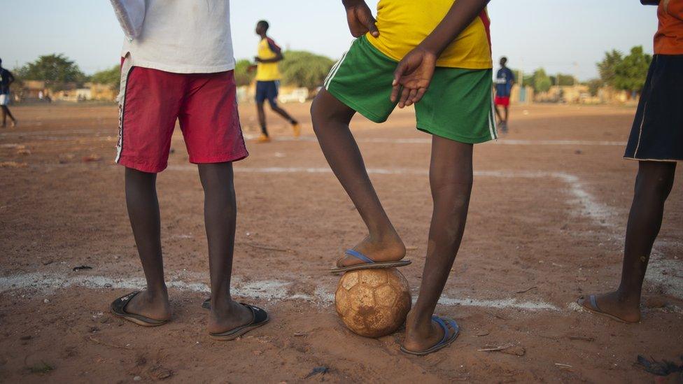 Football players are running after the ball in a football game in the football stadium in Tanghin district in Ouagadougou, Burkina Faso - September 2011