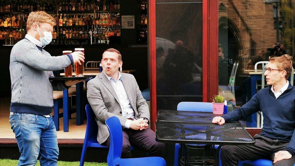 Douglas Ross and colleague are served pints of beer by waiter at Edinburgh bar