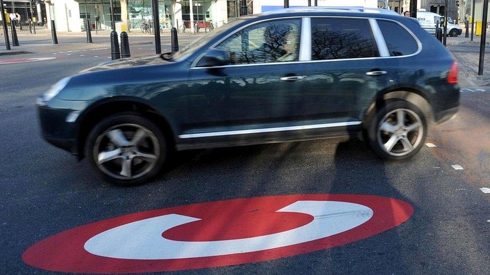 Car driving over congestion zone sign