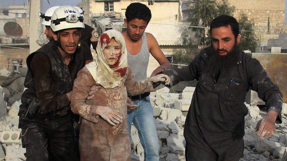 Syrian rescue workers and residents help an injured woman following a reported government air strike on the rebel-held Aleppo district of Haydariya on 10 April 2016