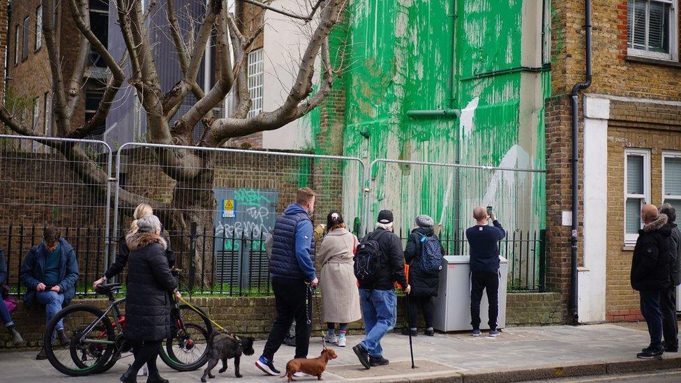 People looking at Banksy artwork