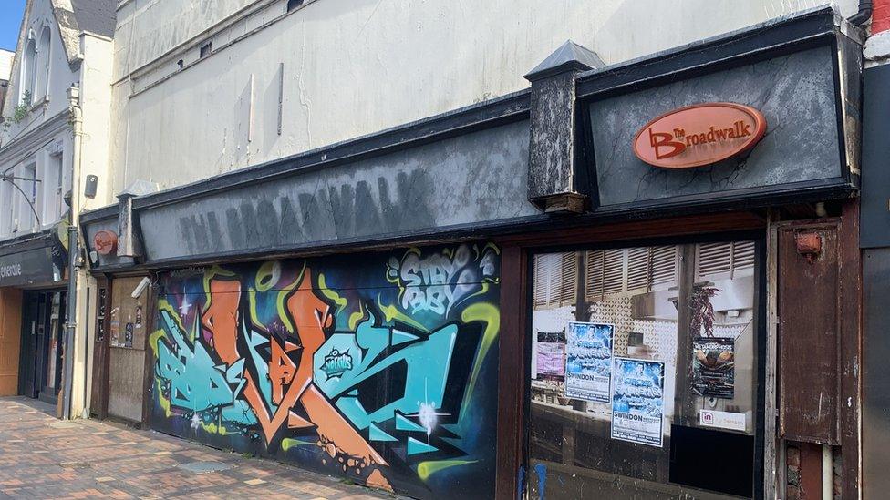 The front of the Broadwalk Bar in Swindon showing decaying wood and graffiti