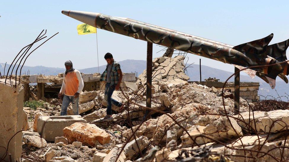 Youths walk past Hezbollah's mock rockets at the former Israeli-run prison of Khiam, which was destroyed in the 2006 war (12 July 2016)