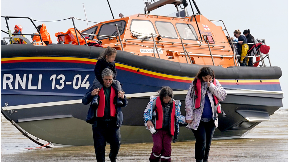 People thought to be migrants walk from RNLI boat up Dungeness beach on 27/4/23