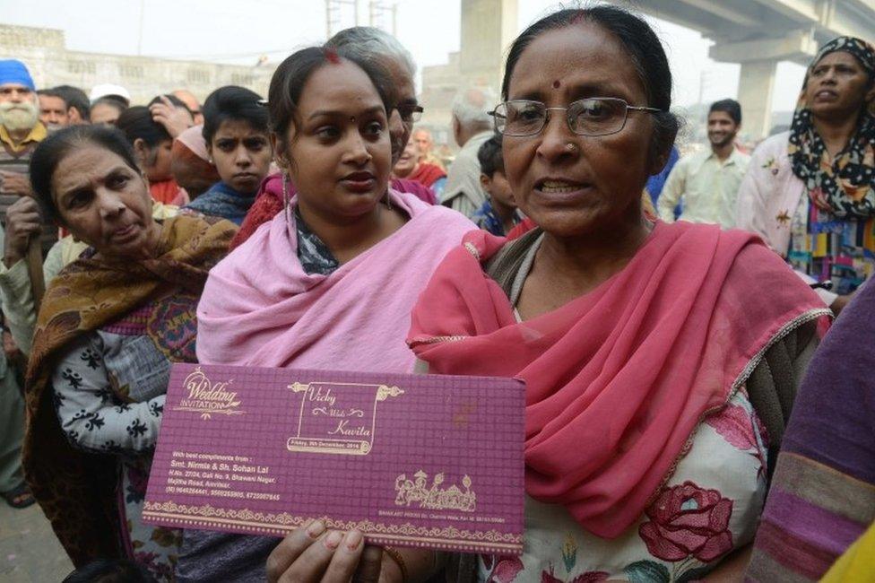 Indian women Nirmla (C) stands in a queue outside bank as she holds her son's wedding invitation card, in hopes of withdrawing money for the event, in Amritsar on November 19, 2016.