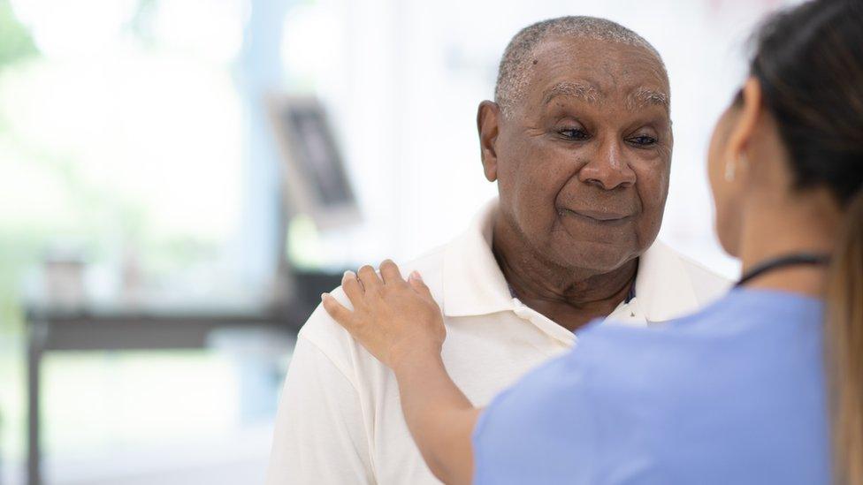 An Elderly Black Gentleman in His Doctors Office Receiving a Check-Up stock photo