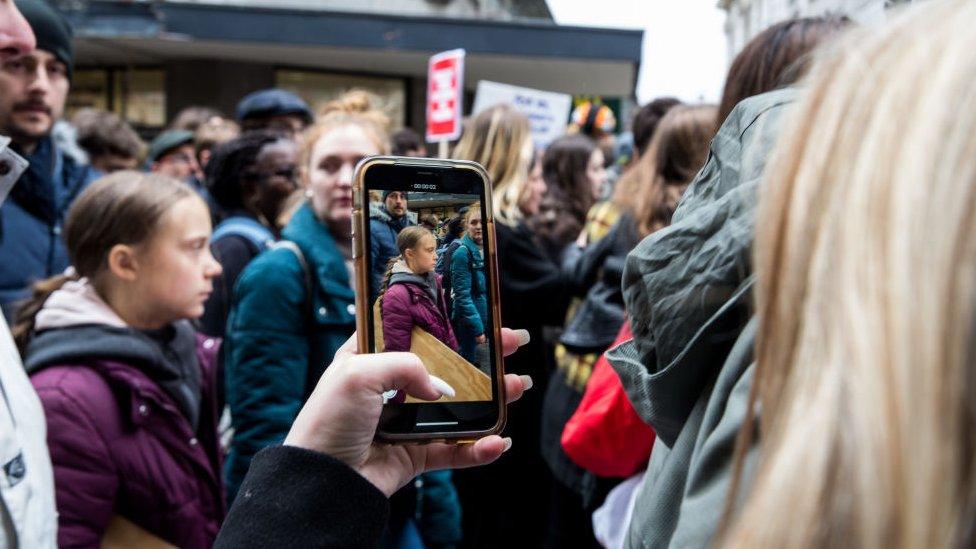 Greta Thunberg seen through a phone screen