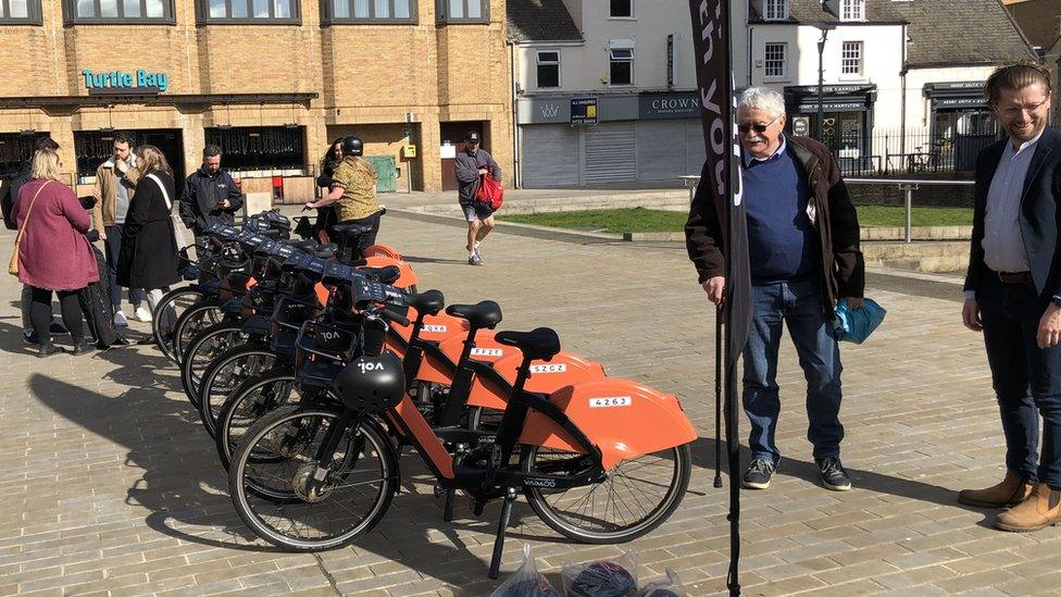 People in Cathedral Square, Peterborough, looking at a number of e-bikes