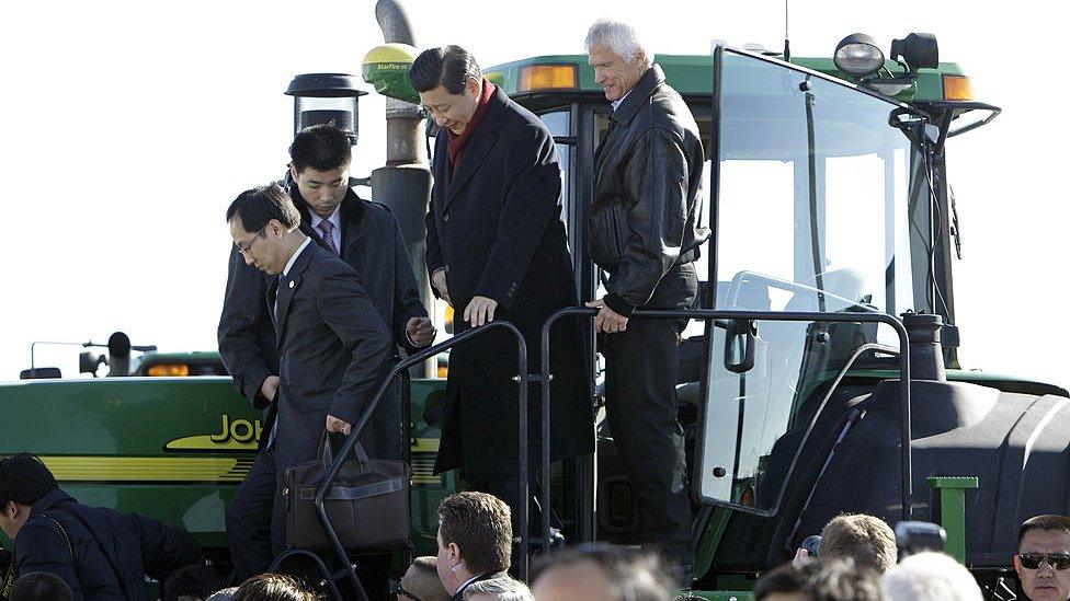 Xi Jinping climbs out of the cab of a tractor with Rick Kimberley while touring his family farm in 2012