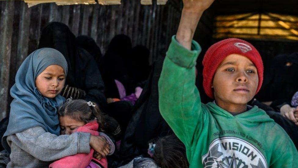 Children and women sit in the back of a lorry waiting to be evacuated