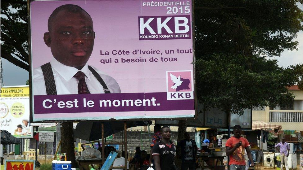 People pass a campaign poster of presidential candidate Kouadio Konan Bertin in Abidjan