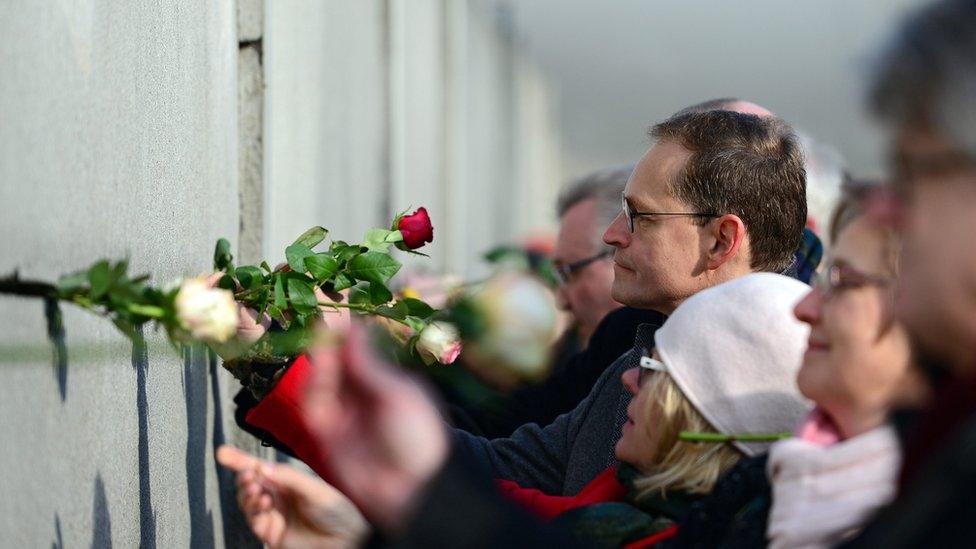 Berlin Mayor Michael Mueller places a rose in a crack during the central event to commemorate the 1989 Peaceful Revolution in the GDR.