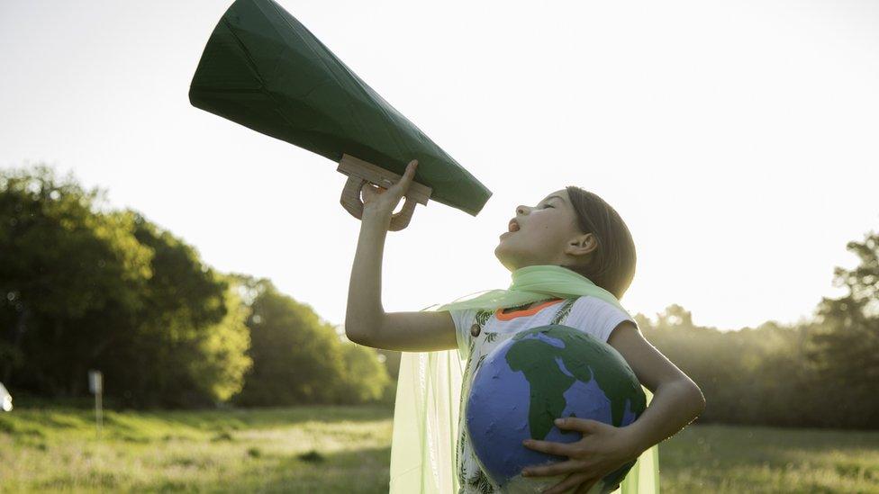 Child holding a paper megaphone and globe.