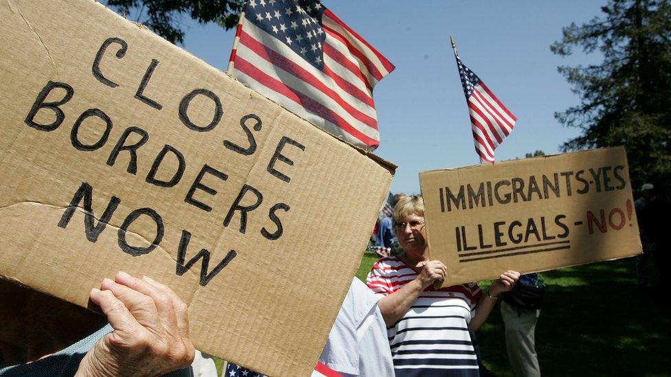 People hold up placards protesting against illegal immigrants