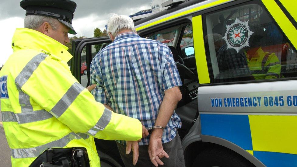 A man in handcuffs is put into a police vehicle