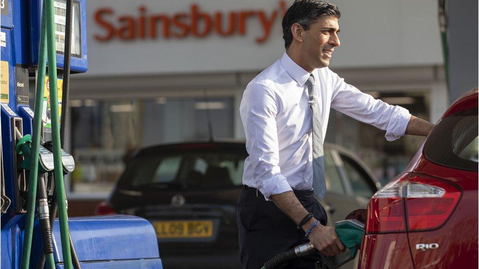 Chancellor Rishi Sunak at a petrol station pump filling a car with petrol.