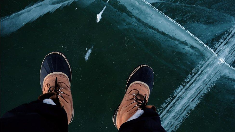 Close up of a man's shoes stood on frozen lake