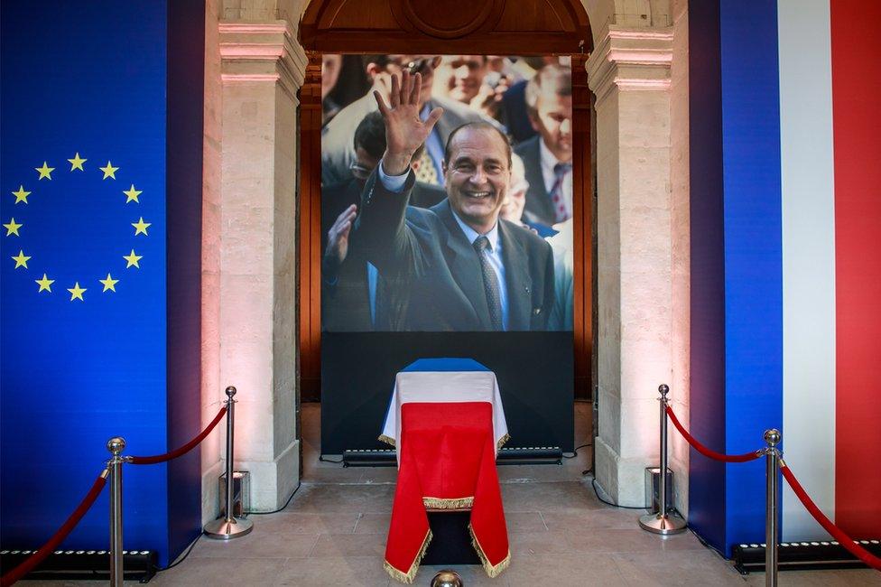 The coffin of former French President Jacques Chirac lies in state in front of a photograph of the late statesman, in the Invalides 29 September 2019.