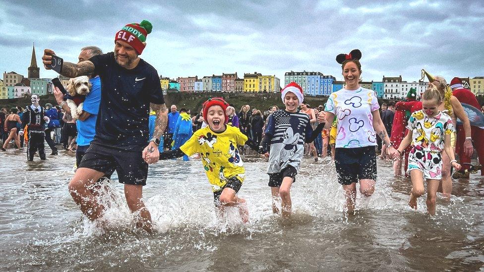 family holding hands and running into the water