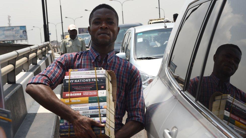 A street vendor sells books on a busy road in Lagos, Nigeria.