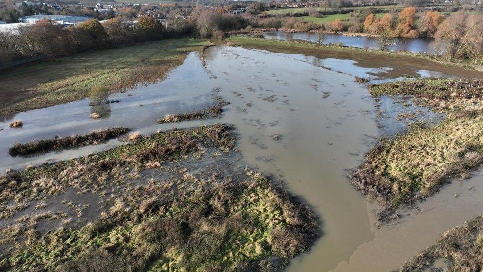 Drone shot of a triangular area of water with buildings in the background