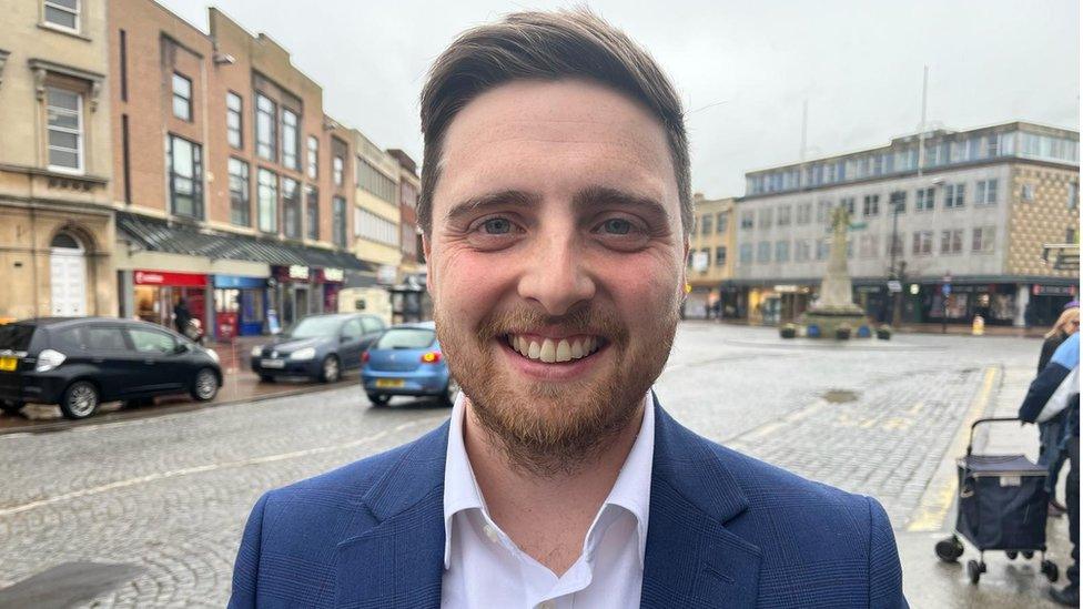 Cllr Tom Deakin, Leader of Taunton Town Council, standing in the town centre smiling at the camera