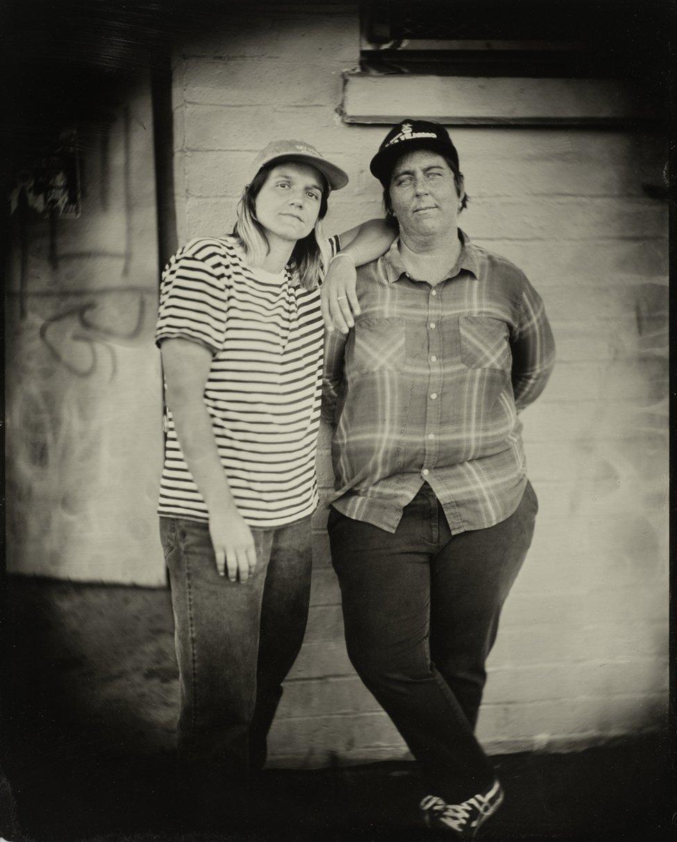 Portrait of two people leaning against a wall