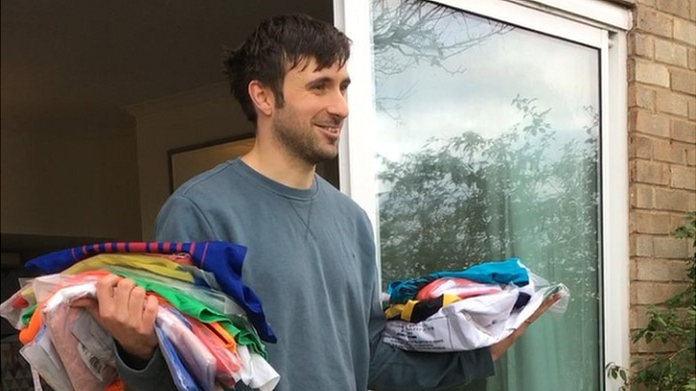 Paul Watson stood in a doorway holding multiple football shirts.