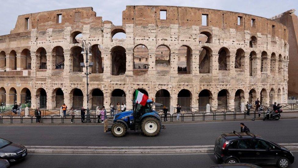 A tractor with an Italian flag attached to it drives past a Colosseum as farmers protest over price pressures, taxes and green regulation, grievances shared by farmers across Europe, in Rome, Italy