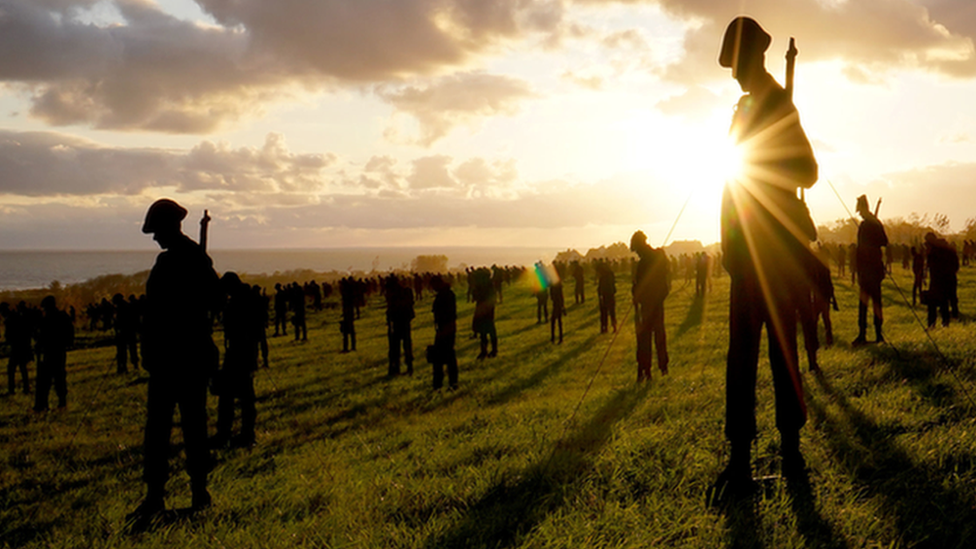 silhouettes of servicemen with sun in background