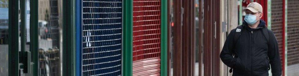 Man in mask walks past empty shops