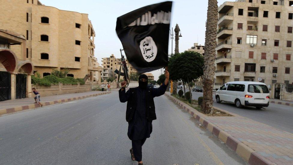 A member loyal to IS waves a flag in Raqqa in June 2014