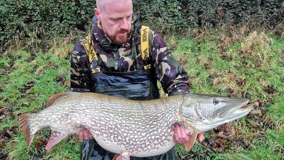 Lloyd Watson wearing a camouflage jacket holding the giant fish