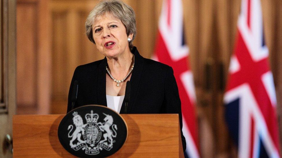 Theresa May stands at podium making speech