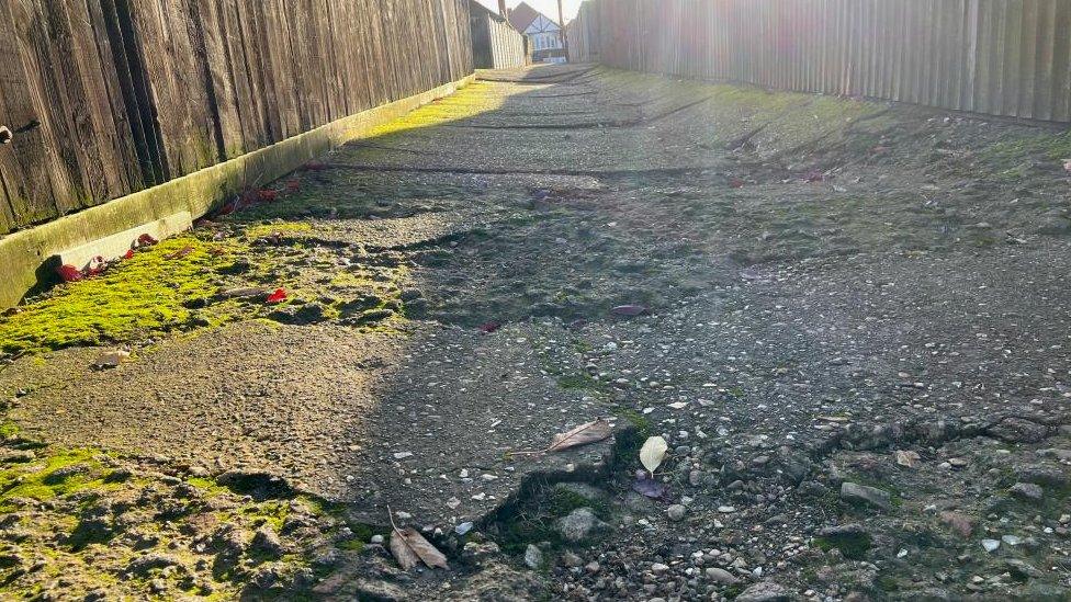 Shot from ground level showing cracked tarmac across the path and moss