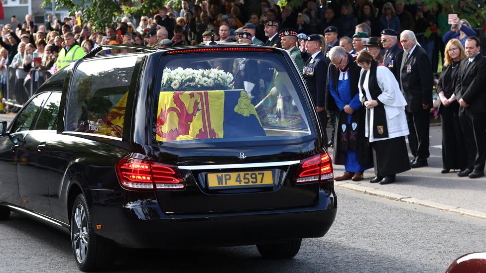 People line the street as the hearse carrying the coffin passes through the village of Ballater, near Balmoral