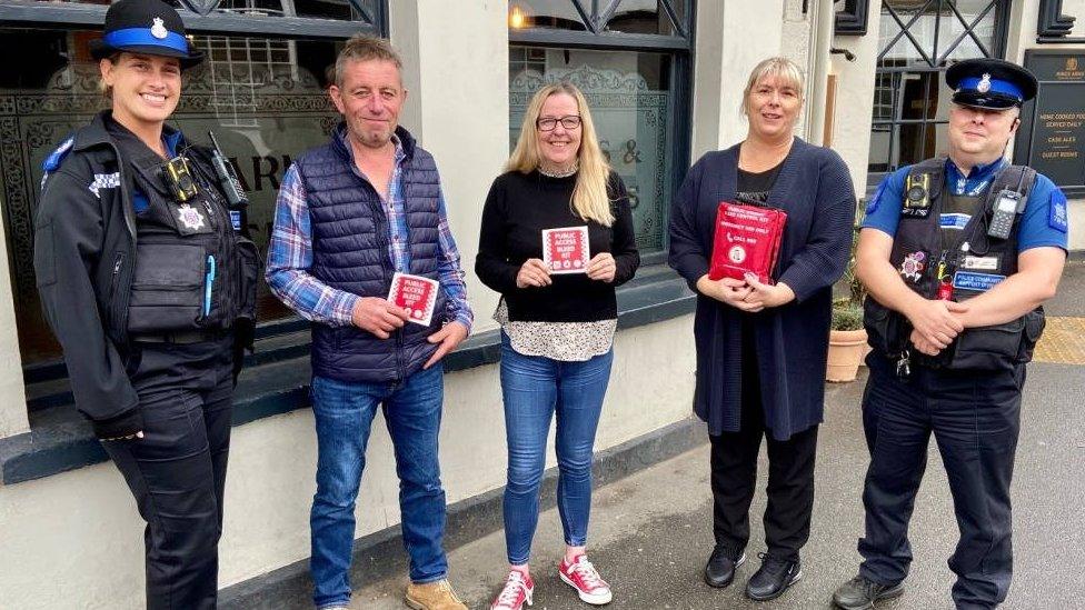 Police and Julie Taylor outside a pub with a bleed kit