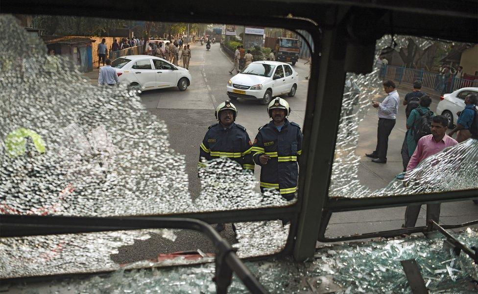 Indian firemen inspect a damaged bus after supporters of the Republican Party of India turned violent during a protest in Mumbai