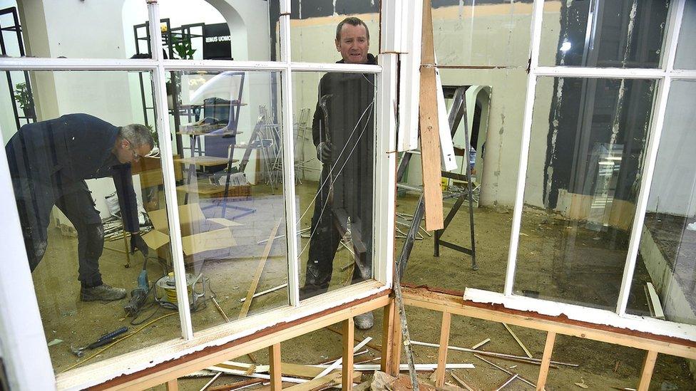 Two men carry out repairs in a business premises that was affected by flooding in Newry