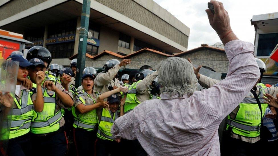 An elderly opposition protester attacks the security forces in Caracas