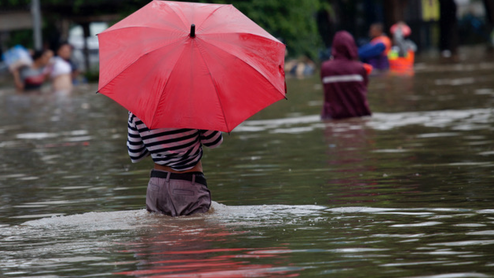 Person standing with umbrella in flooded street