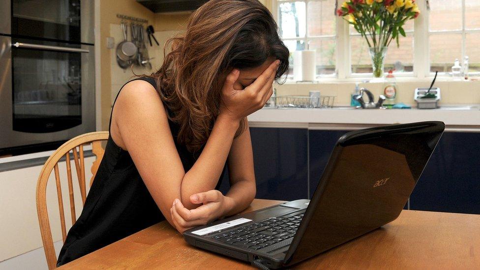 Woman at laptop with head in hands